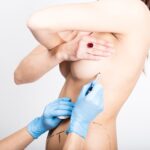 Female doctor makes dotted line on female body for cellulite correction. cosmetic surgery. lifting and breast augmentation