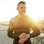 Man stands on beach at sunset in long-sleeve shirt with sculpted chest