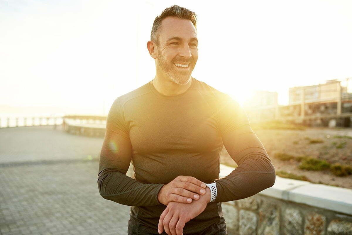 Man stands on beach at sunset in long-sleeve shirt with sculpted chest