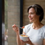 Happy Woman at Home Eating Anti-Inflammatory Diet by Window