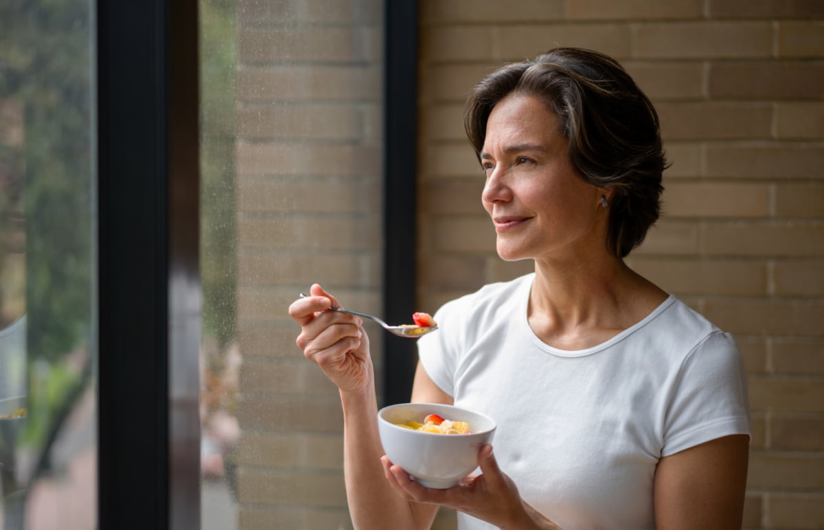 Happy Woman at Home Eating Anti-Inflammatory Diet by Window