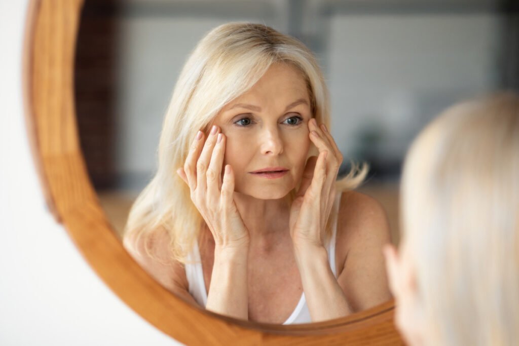 Woman looking in the mirror at eyelids considering blepharoplasty surgery